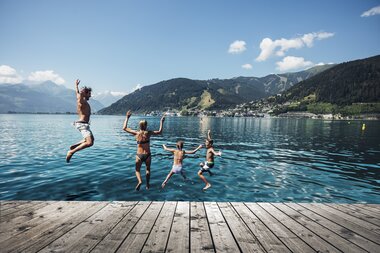 Eine Familie springt vom Steg am Zeller See in den See | © Zell am See-Kaprun Tourismus