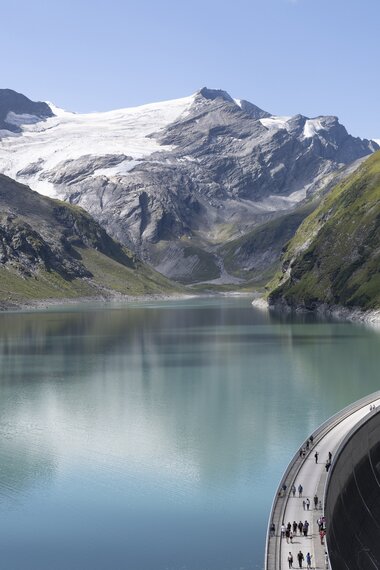 Ansicht des Stausees Kaprun mit der Staumauer in der Mitte, dahinter Stausee und die Berge | © VERBUND, Johannes Wiedl