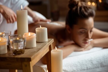 Young lady relaxes behind candles in the spa salon | © Freepik