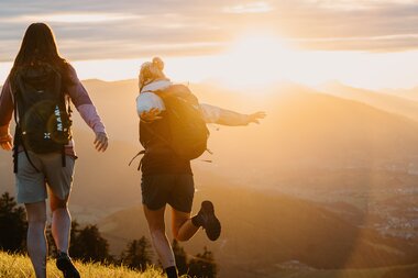 Zwei Wanderer genießen den Sonnenaufgang über den Bergen der Region Hochkönig, voller Abenteuer und Ruhe. | © Hochkönig Tourismus GmbH