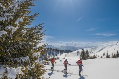 Drei Wanderer genießen den Pulverschnee und die Sonne in den majestätischen Hochkönig Bergen. | © Hochkönig Tourismus GmbH