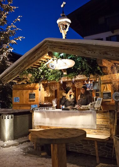 Eine beleuchtete Holzhütte beim Wintermarkt am Hochkönig bei Nacht, einladend und stimmungsvoll in winterlicher Umgebung. | © Hochkönig Tourismus GmbH