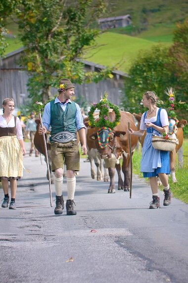 Bunte Almwandlung in der Region Hochkönig, Trachten und Kühe vor Bergkulisse erwecken Tradition und Natur. | © Hochkönig Tourismus GmbH