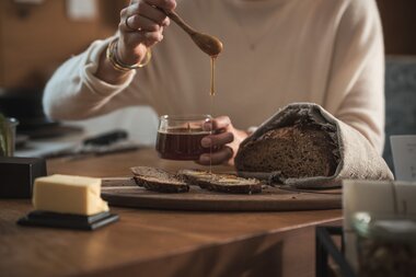 Honig wird auf eine Brotscheibe mit Butter getropft | © Karin Pasterer