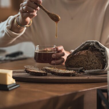 Honig wird auf eine Brotscheibe mit Butter getropft | © Karin Pasterer