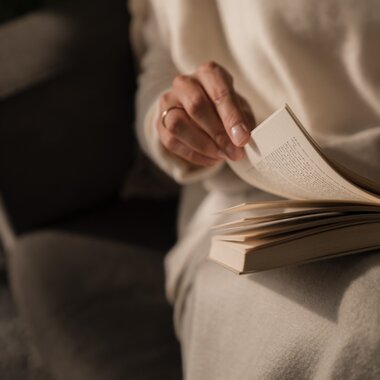 Eine junge Frau sitzt gemütlich auf der Couch und liest ein Buch | © Karin Pasterer