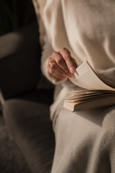 Eine junge Frau sitzt gemütlich auf der Couch und liest ein Buch | © Karin Pasterer