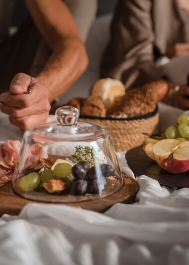 Ein Paar sitzt im Bett und frühstückt verschiedene Aufschnitte und Brot | © Karin Pasterer