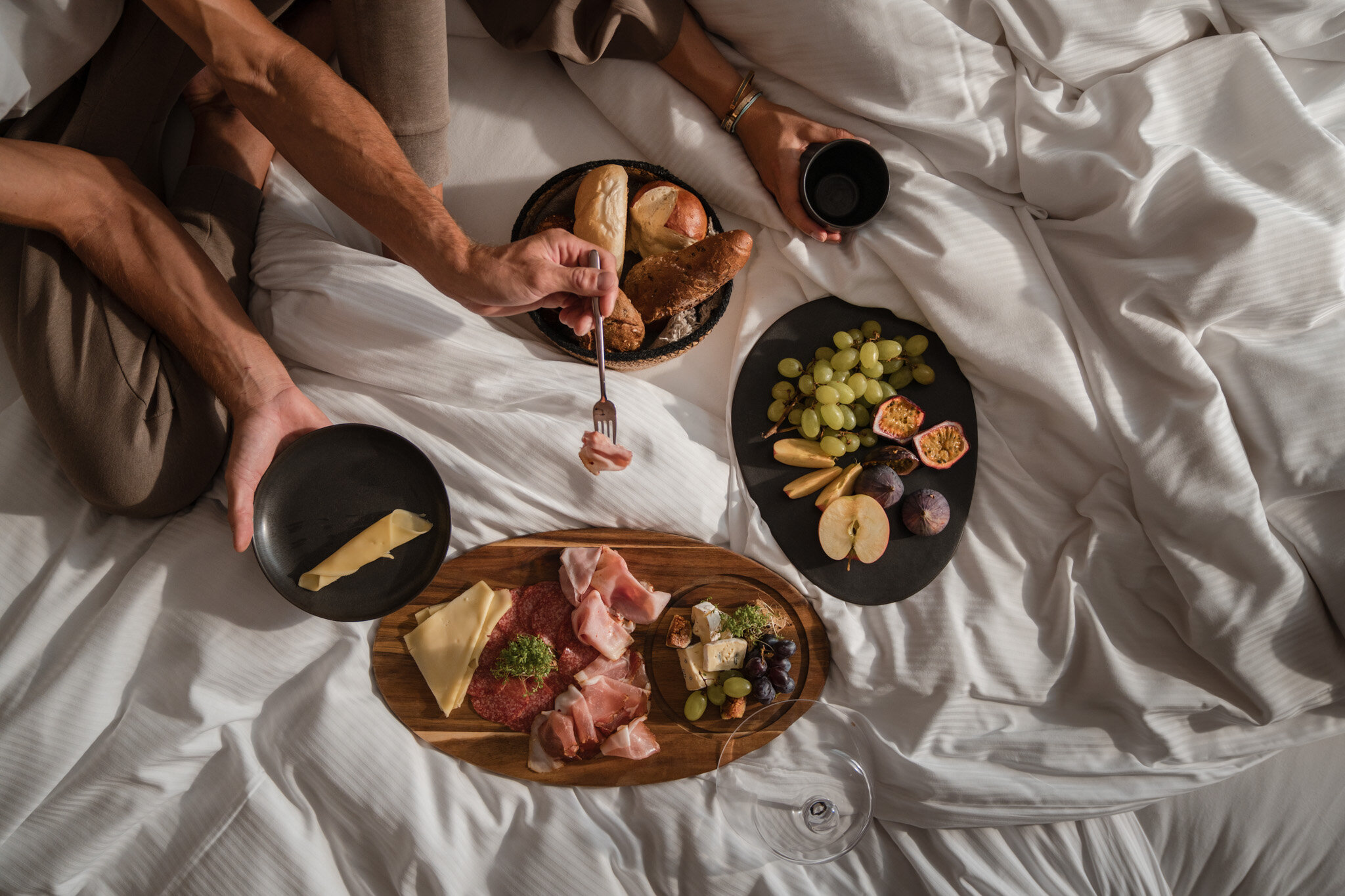 Ein Paar sitzt im Bett und frühstückt verschiedene Aufschnitte und Brot | © Karin Pasterer