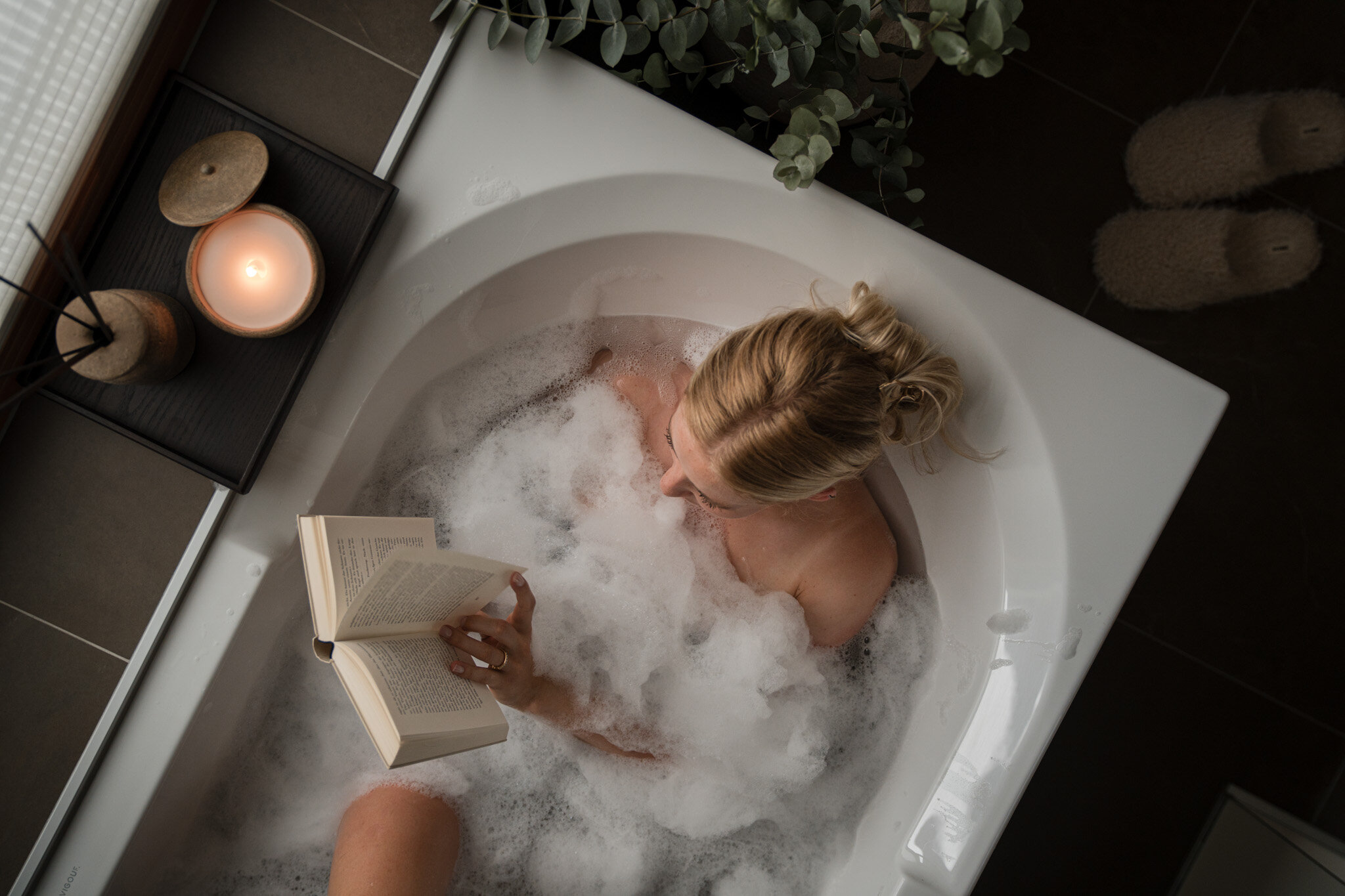 Eine junge Frau sitzt gemütlich in der Badewanne und genießt ein Buch | © Karin Pasterer