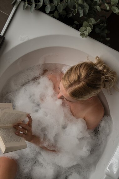 Eine junge Frau sitzt gemütlich in der Badewanne und genießt ein Buch | © Karin Pasterer