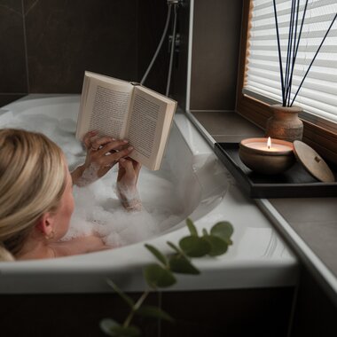 A young woman sits comfortably in the bathtub and enjoys a book. | © Karin Pasterer