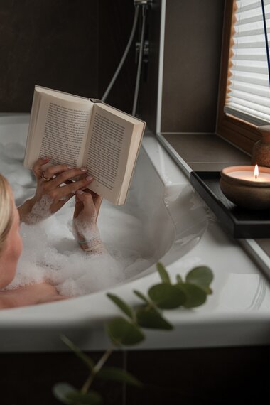 Eine junge Frau sitzt gemütlich in der Badewanne und genießt ein Buch | © Karin Pasterer