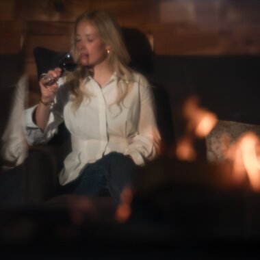 Eine junge Frau genießt Wein beim Kamin | © Karin Pasterer