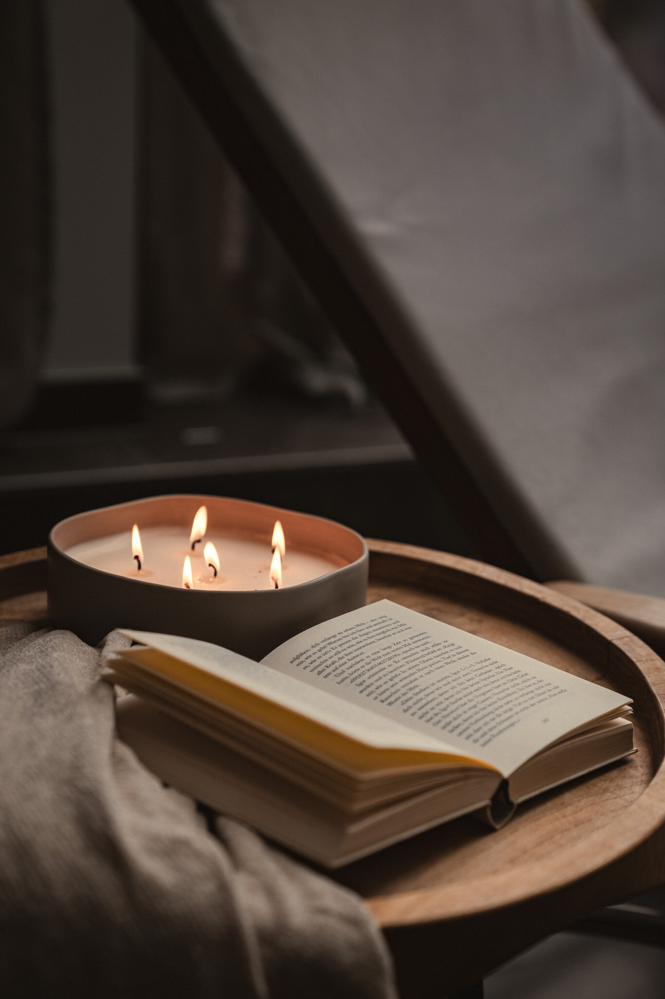 Close-up of an atmospheric candle and an open book on a coffee table | © Karin Pasterer