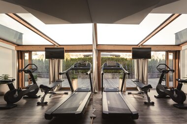 Gym with treadmill, bikes, and benches in front of a huge window | © Karin Pasterer